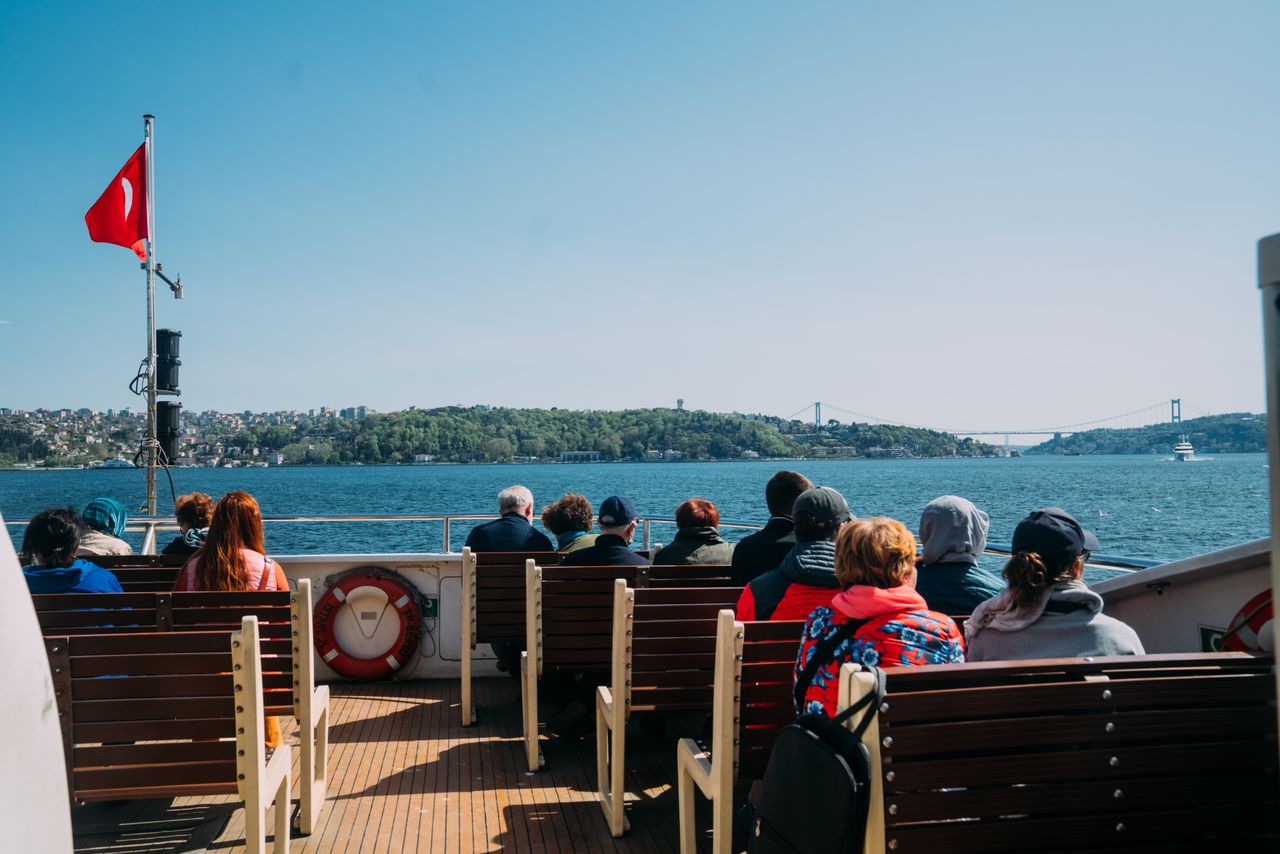 Passengers enjoy a ferry ride on the Bosphorus with scenic views of Istanbul and a clear blue sky.